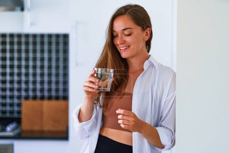 Photo for Portrait of happy young satisfied cute attractive woman drinking a glass of fresh filtered pure water. Healthy daily habits and support water balance - Royalty Free Image