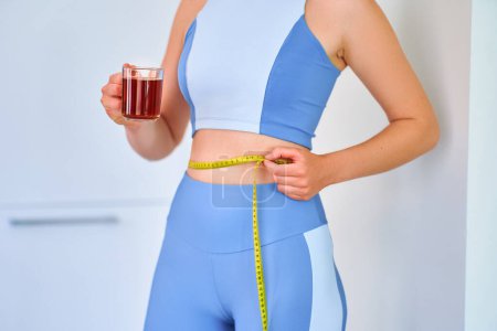 Foto de Fitness mujer deportiva saludable beber té de hierbas para bajar de peso y adelgazar el cuerpo - Imagen libre de derechos