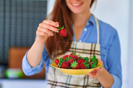 Foto de Placa de retención femenina con fresas orgánicas maduras frescas en la cocina casera - Imagen libre de derechos