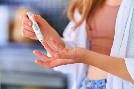 Foto de Hembra que usa lanceter en el dedo para medir y comprobar el nivel de glucosa en sangre. Atención sanitaria y tratamiento de la diabetes mellitus - Imagen libre de derechos