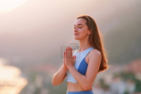 Photo for Inspired hopeful serene female meditate with closed eyes and standing alone with praying hands at sunset. Relief stress and clean healthy minds - Royalty Free Image