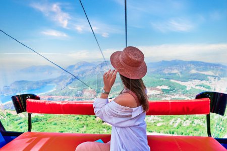 Photo for Girt tourist traveler sitting in cable car cabin during trip to viewpoints in the mountains - Royalty Free Image