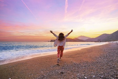 Photo for Happy carefree one alone joyful girl running with open arms on the beach at sunset. Beautiful moment life vacation - Royalty Free Image