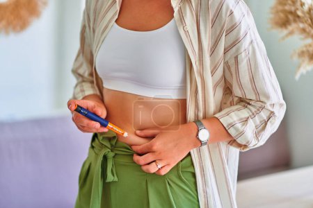 Foto de Mujer diabética joven inyectándose insulina en el vientre - Imagen libre de derechos