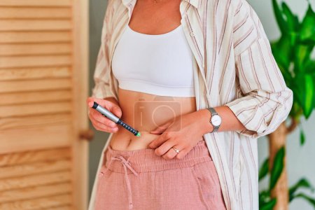 Foto de Mujer diabética joven inyectándose insulina en el vientre - Imagen libre de derechos