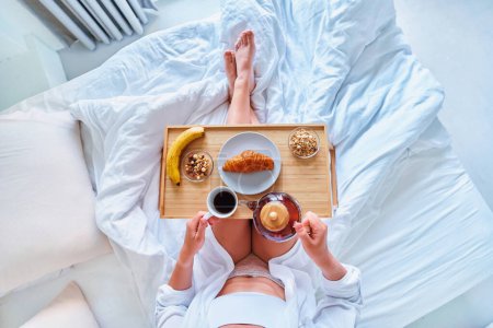 Foto de Mujer despierta disfrutar del desayuno en la cama en la mañana cómoda perezoso acogedor - Imagen libre de derechos
