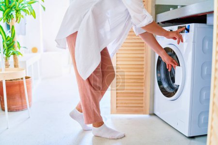 Foto de Mujer que usa una lavadora moderna para lavar en casa - Imagen libre de derechos