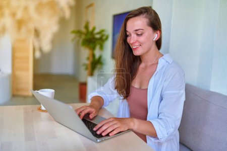 Foto de Joven feliz alegre inteligente moderno sonriente linda chica satisfecha utilizando la computadora en el interior del hogar - Imagen libre de derechos