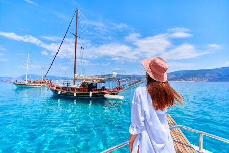 Photo for Traveler girl enjoys relaxing vacation on a boat in the turquoise sea - Royalty Free Image
