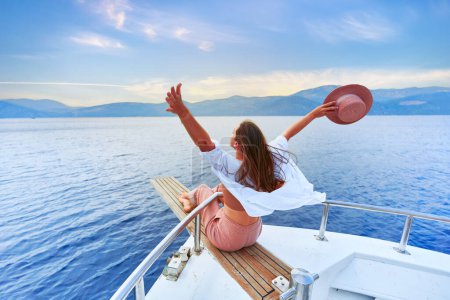 Téléchargez les photos : Gratuit insouciant satisfait heureux inspiré voyageur fille à bras ouverts bénéficie de vacances reposantes sur un bateau privé blanc dans la mer turquoise - en image libre de droit