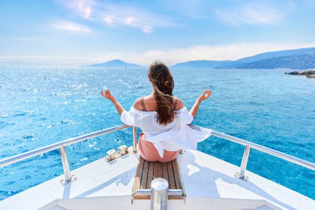 Téléchargez les photos : Fille voyageur inspiré insouciant gratuit bénéficie de vacances privées relaxantes et calmes sur un bateau de luxe blanc dans la mer turquoise - en image libre de droit