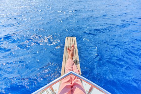 Photo for Legs of free carefree traveler girl while enjoying relaxing and calm private vacay on a boat in the turquoise sea - Royalty Free Image