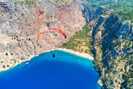 Téléchargez les photos : Paysage de parapente volant parmi les montagnes dans la baie de la mer bleue à la journée ensoleillée d'été - en image libre de droit