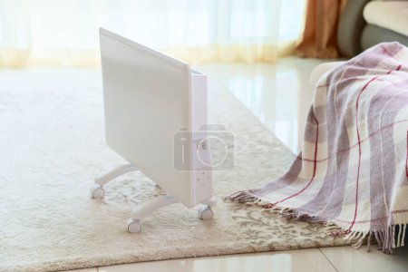 Foto de Moderno calentador eléctrico portátil blanco en la alfombra del suelo en la sala de estar - Imagen libre de derechos