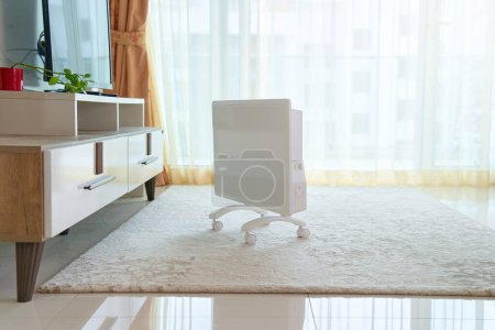 Foto de Moderno calentador eléctrico portátil blanco en la alfombra del suelo en la sala de estar - Imagen libre de derechos