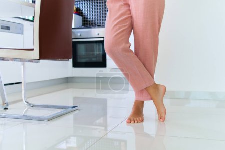 Foto de Mujeres piernas descalzas en calefacción por suelo radiante en casa cocina - Imagen libre de derechos