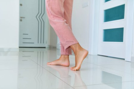 Foto de Mujeres piernas descalzas en el suelo caliente caliente en la sala de estar en casa - Imagen libre de derechos