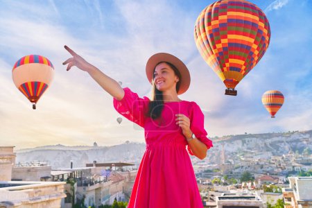 Photo for Portrait of happy girl traveler vacations beautiful destination in Goreme, Turkey. Fabulous Kapadokya with flying air balloons at sunrise, Anatolia - Royalty Free Image