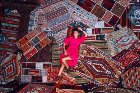 Photo for Boho girl traveler vacations at beautiful destination in Goreme, Nevsehir. Room with traditional Turkish carpets in Kapadokya, Anatolia - Royalty Free Image