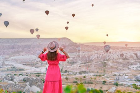 Photo for Back of free carefree happy inspired girl traveler walking in valley in Anatolia, Kapadokya. Flying air balloons at beautiful destination in Nevsehir, Goreme - Royalty Free Image