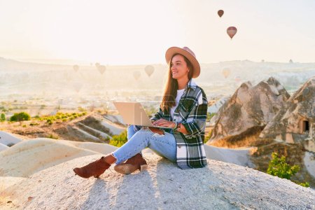 Photo for Freelancer working online at beautiful destination in Nevsehir, Goreme. Free inspired traveling blogger sitting alone on hill in scenic valley in Anatolia, Kapadokya - Royalty Free Image