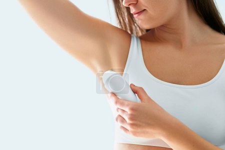 Téléchargez les photos : Femme utilisant un déodorant bâton pour la protection de la transpiration - en image libre de droit
