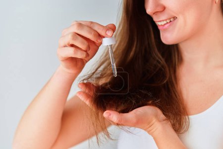 Frau verwendet Serum für schönes gesundes Haar 