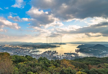 Photo for Bird's-eye view from the deck of the Yumiharidake Observation Point overlooking the Sasebo shipyard with the Kujukushima islands off coasts in background at sunset. - Royalty Free Image