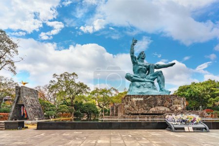 Téléchargez les photos : Nagasaki, kyushu - dec 11 2021 : Statue de paix créée par le sculpteur japonais Seibo Kitamura inspirée par l'athlète Hiroichi Yoshida à côté de la tour Orizuru no ornée de mille grues origami. - en image libre de droit