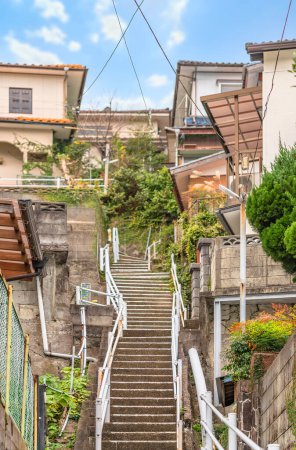 Téléchargez les photos : Une pente raide avec un escalier étroit qui monte entre les maisons japonaises empilées sur les coteaux du parc Kazagashira menant à la célèbre rue Sakamoto Ryoma à Nagasaki. - en image libre de droit