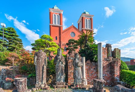 Téléchargez les photos : Nagasaki, kyushu - dec 11 2022: A-bombed remains of the former Urakami Cathedral destroyed by the atomic bomb in front of the brick facade of the actual Roman Catholic Immaculate Conception Cathedral. - en image libre de droit