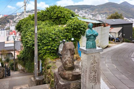 Téléchargez les photos : Nagasaki, kyushu - 14 décembre 2022 : Petite statue en bronze du samouraï japonais Sakamoto Ryoma en kimono avec son nom gravé sur un piédestal en pierre dans une ruelle du parc Kazagashira. - en image libre de droit