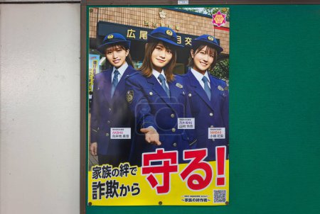 Téléchargez les photos : Tokyo, Japon - 24 décembre 2022 : Des idoles japonaises des AKB48 habillées en uniforme de police sur une affiche de prévention d'un poste de police pour empêcher les personnes âgées d'être ciblées par des criminels par fraude téléphonique. - en image libre de droit