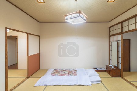 Téléchargez les photos : A typical traditional Japanese bedroom characterized by tatami mats, shoji doors, fusuma walls, futon mattress and minimalist decorations, creating a peaceful and serene atmosphere. - en image libre de droit