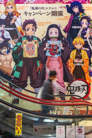 Téléchargez les photos : Tokyo, japan - october 27 2022: Escalator wall of a game center decorated with a campaign poster depicting characters of Japanese manga and anime Kimetsu no Yaiba or Demon Slayer by Koyoharu Gotouge. - en image libre de droit