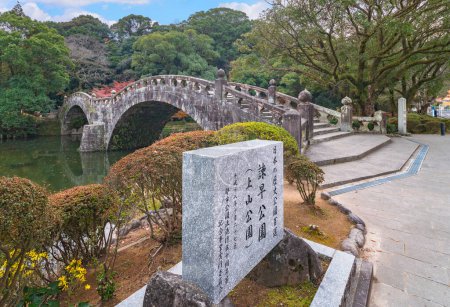 Téléchargez les photos : Nagasaki, kyushu - 10 décembre 2022 : Le Meganebashi symétrique, également connu sous le nom de Spectacles Stone Bridge, jette son reflet dans l'étang situé au parc Isahaya le long de la rivière Honmyo dans la ville d'Isahaya. - en image libre de droit