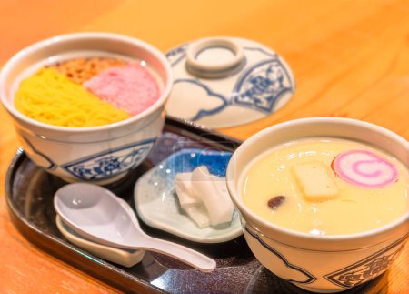 Foto de Cocina tradicional japonesa de natillas de huevo Chawanmushi con sakura denbu rosa, crepe de huevo triturado de tamago kinshi y cerdo molido de buta soboro en tazones pequeños. - Imagen libre de derechos
