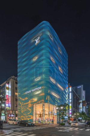 Photo for Tokyo, japan - april 11 2023: Night view of the Louis Vuitton Ginza store building designed by architects Jun Aoki and Peter Marino fully covered of holographic glass with emerald blue highlights. - Royalty Free Image