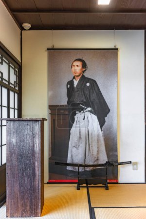Téléchargez les photos : Nagasaki, kyushu - dec 14 2022 : Lieu photo touristique au musée commémoratif Nagasaki Kameyama Shachu avec une affiche suspendue du samouraï japonais Sakamoto Ryoma et son épée katana sur un tatami mat. - en image libre de droit