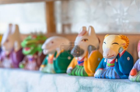 Téléchargez les photos : Figurines en céramique des douze signes du zodiaque japonais ou juunishi représentés comme des animaux amusants du cycle sexagénaire et se concentrant sur les moutons portant un kimono hakama crêpé traditionnel coloré. - en image libre de droit