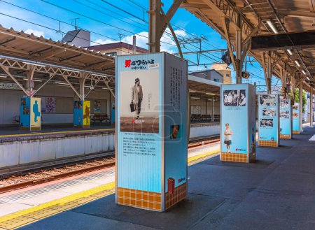 Téléchargez les photos : Tokyo, Japon - 18 juillet 2023 : Plate-forme ferroviaire de la gare de Shibamata dont les piliers sont décorés avec des pancartes mettant en vedette la célèbre série de films japonais Otoko wa tsurai yo avec Tora-san. - en image libre de droit