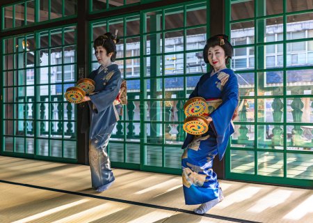 Foto de Nagasaki, kyushu - dic 14 2022: Evento gratuito con dos mujeres japonesas de mediana edad que usan kimono y sostienen panderetas furi-dutsumi en los primeros barrios capitanes de barcos de la isla de Dejima. - Imagen libre de derechos