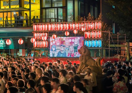 Foto de Tokyo, akihabara - 11 ago 2023: Multitud iluminada por la noche por linternas aparte de una pantalla de difusión que muestra personajes de manga durante el Festival de Danza Anime Song Bon Odori celebrado en Kanda Myojin Shrine. - Imagen libre de derechos