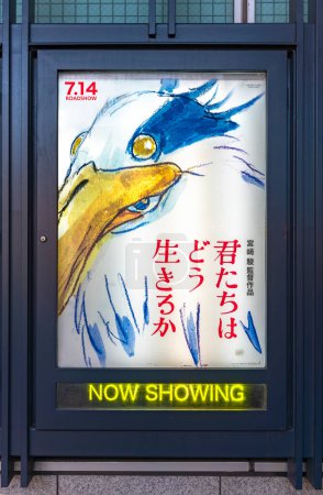 Téléchargez les photos : Tokyo, shinjuku - août 07 2023 : Affiche de cinéma rétroéclairée du film d'animation japonais "Le Garçon et le Héron" écrit par Hayao Miyazaki du Studio Ghibli avec un néon écrit "montrant maintenant". - en image libre de droit