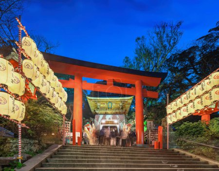 Photo for Kanagawa, enoshima - dec 25 2022: Low angle of the stairs lined with lit paper lanterns lined up leading to Enoshima Shrine's torii gate and gold-leafed Zuishinmon gate crowded with tourists at dusk. - Royalty Free Image