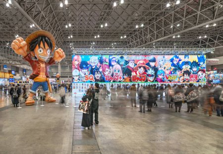 Téléchargez les photos : Chiba, japon - dec 18 2022 : Caractère manga gonflable de la série animée japonaise One Piece levant les bras dans l'air accueillant les consommateurs à côté d'une énorme pancarte mettant en vedette des héros de manga à la convention Jump Festa. - en image libre de droit
