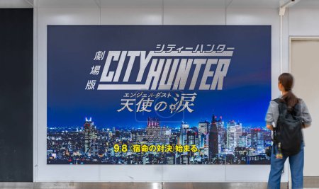 Photo for Tokyo, japan - sep 08 2023: A pedestrian looking at a large poster in Shinjuku Station depicting a night cityscape of Shinjuku ward from Japanese anime Angel Dust adapted from manga City Hunter. - Royalty Free Image