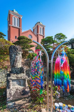 Téléchargez les photos : Nagasaki, kyushu - dec 11 2023 : Reste bombardé de l'ancienne cathédrale Urakami à côté de mille grues origami décorations avec la façade en brique de la cathédrale catholique Immaculée Conception. - en image libre de droit