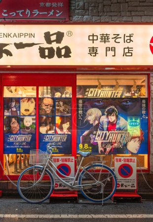 Téléchargez les photos : Tokyo, shinjuku - sep 08 2023 : Vélo stationné illégalement à côté d'une façade chinoise du restaurant Soba ornée d'affiches de l'anime japonais Angel Dust adaptées du manga City Hunter alias Nicky Larson. - en image libre de droit