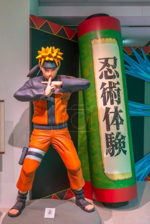 Téléchargez les photos : Ikebukuro, Japon - 16 jan 2024 : Figurine de manga grandeur nature du ninja Naruto faisant une attaque de jutsu à côté d'un rouleau écrit 'Experience Ninja Martial Art' à l'exposition gratuite de la gare d'Anime Tokyo. - en image libre de droit